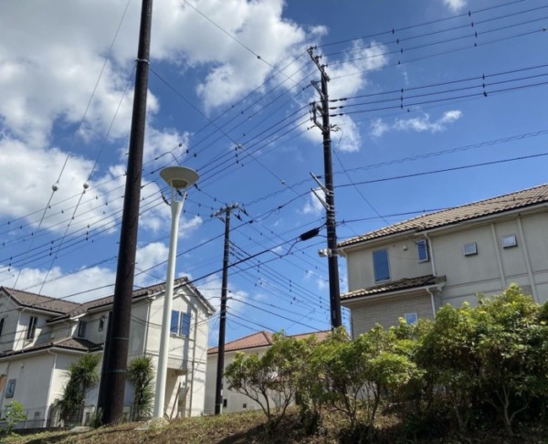 電線が多くはりめぐらされている住宅と電柱の写真
